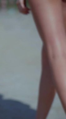 Sahilde bikinili genç bir kadın. Dikey. Esnek kalçalı bir kız kumsalda güneşleniyor. Çekici, ince model kameraya poz veriyor. Bikinili bir kadın kumsalda dinleniyor. Bikinili güzellik plaj havasından zevk alıyor..