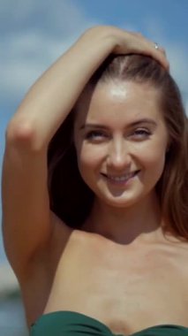 Sahilde bikinili genç bir kadın. Dikey. Esnek kalçalı bir kız kumsalda güneşleniyor. Çekici, ince model kameraya poz veriyor. Bikinili bir kadın kumsalda dinleniyor. Bikinili güzellik plaj havasından zevk alıyor..
