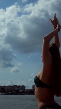 Sahilde bikinili genç bir kadın. Dikey. Esnek kalçalı bir kız kumsalda güneşleniyor. Çekici, ince model kameraya poz veriyor. Bikinili bir kadın kumsalda dinleniyor. Bikinili güzellik plaj havasından zevk alıyor..