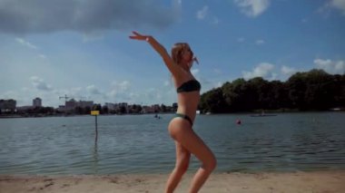 Güneşli sahilde bikinili genç bir kadın koşuyor. Esnek kalçalı bir kız kumsalda güneşleniyor. Çekici, ince model kameraya poz veriyor. Bikinili bir kadın kumsalda dinleniyor. Bikinili güzellik plaj havasından zevk alıyor..