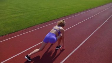 Stadyumda koşan genç bir kadın. Pistte koşan bayan sporcu. Koşu pistinde koşan güzel bir bayan atlet. Şortlu kararlı bir kadın ve güneşli havalarda her şey yolunda. Kadın model koşucu iş başında. Başlar