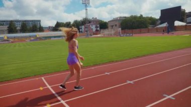 Stadyumda koşan genç bir kadın. Pistte koşan bayan sporcu. Koşu pistinde koşan güzel bir bayan atlet. Şortlu kararlı bir kadın ve güneşli havalarda her şey yolunda. Kadın model koşucu iş başında. Başlar
