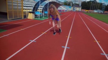 Stadyumda koşan genç bir kadın. Pistte koşan bayan sporcu. Koşu pistinde koşan güzel bir bayan atlet. Şortlu kararlı bir kadın ve güneşli havalarda her şey yolunda. Kadın model koşucu iş başında. Başlar