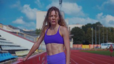 Genç bir kadın antrenmana hazırlanıyor. Spor meraklısı koşu parkurunda topallıyor. Hareketli kadın egzersiz öncesi esneme hareketleri yapıyor. Koşucu sporcu esneme hareketleriyle ısınıyor. Dişi koşucu ön koşular yapıyor