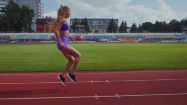 Genç bir kadın antrenmana hazırlanıyor. Spor meraklısı koşu parkurunda topallıyor. Hareketli kadın egzersiz öncesi esneme hareketleri yapıyor. Koşucu sporcu esneme hareketleriyle ısınıyor. Dişi koşucu ön koşular yapıyor