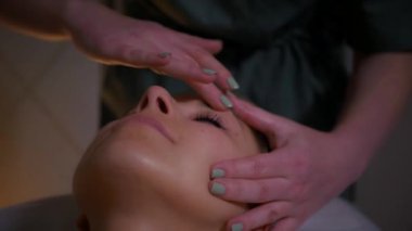 Güzel çıplak kız yüzüne rahatlatıcı bir masaj yaptırıyor. Tanımlanamayan genç bir kadın spa salonunda profesyonel sırt masajı yaptırıyor. Yakın plan çekim. Lüks profesyonel masaj anlayışı. Ağır çekimde çekmek.
