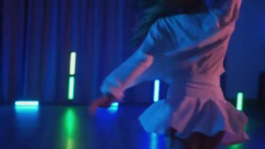 Beyaz şeffaf elbiseli, erotik dans eden ve yüksek topuklu ayakkabı giyen genç bir kadın. Siyah şortlu yarı traşlı kız karanlık uzayda zarafetle hareket ediyor. Sahnedeki bir disko kulübünde striptiz. Kadın dansçı, siluet karşısında 