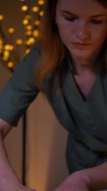 Dikey, güzel çıplak kız sırtına, bacaklarına ve ellerine masaj yaptırıyor. Tanımlanamayan genç bir kadın spa salonunda profesyonel sırt masajı yaptırıyor. Yakın plan çekim. Lüks profesyonel masaj anlayışı. Ağır çekimde çekmek.