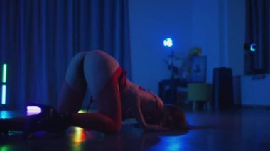 Kırmızı iç çamaşırlı, erotik dans eden, yüksek topuklu genç bir kadın. Siyah şortlu yarı traşlı kız karanlık uzayda zarafetle hareket ediyor. Sahnedeki bir disko kulübünde striptiz. Şerefe kadın dansçı, siluetli ağır çekim