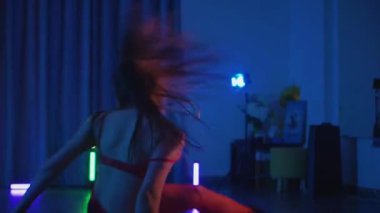 Kırmızı iç çamaşırlı, erotik dans eden, yüksek topuklu genç bir kadın. Siyah şortlu yarı traşlı kız karanlık uzayda zarafetle hareket ediyor. Sahnedeki bir disko kulübünde striptiz. Şerefe kadın dansçı, siluetli ağır çekim