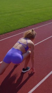 Dikey. Stadyumda koşan genç bir kadın. Pistte koşan bayan sporcu. Koşu pistinde koşan güzel bir bayan atlet. Şortlu kararlı bir kadın ve güneşli havalarda yolda..