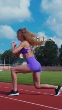 Dikey. Genç bir kadın antrenmana hazırlanıyor. Spor meraklısı koşu parkurunda topallıyor. Hareketli kadın egzersiz öncesi esneme hareketleri yapıyor.. 