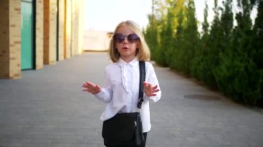 Beyaz gömlekli ve siyah pantolonlu genç bir kız sokaktaki bir iş merkezinin arka planında komik bir şekilde dans ediyor. Genç iş kadını mutlu. Şehir merkezinde kaldırımda yürürken kendi dünyasına dalmış şık bir çocuk..