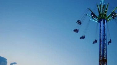 Gece gökyüzüne karşı parlayan ışıklarla süslenmiş canlı bir eğlence gezisi. Luna Parkı. Parlak yeşil ışıklar lunaparktaki dönen bir atlıkarıncanın üzerinde dans ediyor. Ekstrem atlıkarınca neşeyle döner, büyüleyici yeşil ışıklarla aydınlatılır. çekim gücü