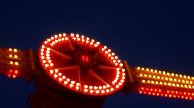 Gece gökyüzüne karşı parlayan ışıklarla süslenmiş canlı bir eğlence gezisi. Luna Parkı. Parlak yeşil ışıklar lunaparktaki dönen bir atlıkarıncanın üzerinde dans ediyor. Ekstrem atlıkarınca neşeyle döner, büyüleyici yeşil ışıklarla aydınlatılır. çekim gücü