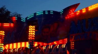 Gece gökyüzüne karşı parlayan ışıklarla süslenmiş canlı bir eğlence gezisi. Luna Parkı. Parlak yeşil ışıklar lunaparktaki dönen bir atlıkarıncanın üzerinde dans ediyor. Ekstrem atlıkarınca neşeyle döner, büyüleyici yeşil ışıklarla aydınlatılır. çekim gücü