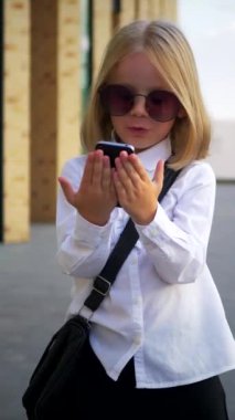 Dikey olarak, genç bir kız elinde telefonuyla mutlu, komik bir şekilde dans ediyor ve kulaklıklarıyla müziğin tadını çıkarıyor. Genç bir iş kadını mutlu, iş yerinin yakınında telefonu elinde tutuyor.