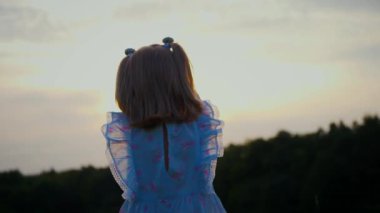 Mavi elbiseli küçük bir kız güneşli bir alanda mutlu mesut duruyor. Açık mavi elbiseli genç bir kız bir tarlada uzun otlarla çevrili olarak yürüyor. Resimli bir tarlada oynayan mavi elbiseli küçük bir kız. Mavi elbiseli bir çocuk, neşeyle