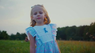 Mavi elbiseli küçük bir kız güneşli bir alanda mutlu mesut duruyor. Açık mavi elbiseli genç bir kız bir tarlada uzun otlarla çevrili olarak yürüyor. Resimli bir tarlada oynayan mavi elbiseli küçük bir kız. Mavi elbiseli bir çocuk, neşeyle