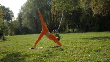 Esneklik eğitimi, Limbering rutinleri, hareket çeşitliliği tatbikatları, müşterek seferberlik tatbikatları, esneklik egzersizleri. Yoga yaparken parkta gerinen turuncu kıyafetli bir kadın. Bir kadın esneme egzersizleri yapar.