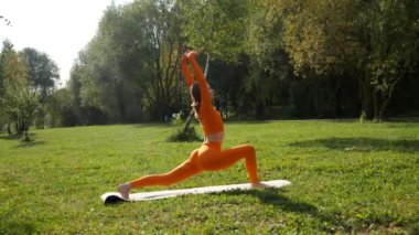 Esneklik eğitimi, Limbering rutinleri, hareket çeşitliliği tatbikatları, müşterek seferberlik tatbikatları, esneklik egzersizleri. Yoga yaparken parkta gerinen turuncu kıyafetli bir kadın. Bir kadın esneme egzersizleri yapar.