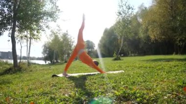 Esneklik eğitimi, Limbering rutinleri, hareket çeşitliliği tatbikatları, müşterek seferberlik tatbikatları, esneklik egzersizleri. Yoga yaparken parkta gerinen turuncu kıyafetli bir kadın. Bir kadın esneme egzersizleri yapar.