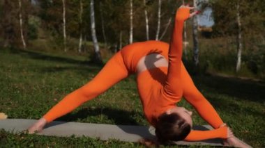 Esneklik eğitimi, Limbering rutinleri, hareket çeşitliliği tatbikatları, müşterek seferberlik tatbikatları, esneklik egzersizleri. Yoga yaparken parkta gerinen turuncu kıyafetli bir kadın. Bir kadın esneme egzersizleri yapar.