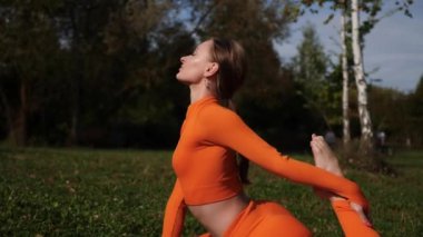 Esneklik eğitimi, Limbering rutinleri, hareket çeşitliliği tatbikatları, müşterek seferberlik tatbikatları, esneklik egzersizleri. Yoga yaparken parkta gerinen turuncu kıyafetli bir kadın. Bir kadın esneme egzersizleri yapar.