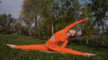 Esneklik eğitimi, Limbering rutinleri, hareket çeşitliliği tatbikatları, müşterek seferberlik tatbikatları, esneklik egzersizleri. Yoga yaparken parkta gerinen turuncu kıyafetli bir kadın. Bir kadın esneme egzersizleri yapar.