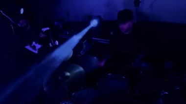 Davulcu cool rock konserini çalar. Aksiyon kamerasından bak, profesyonel ol. Bir adam sahnede enerjik bir şekilde davul çalıyor arkasında parlak ışıklar yanıyor. Canlı performans sergileyen bir davulcu, renkli sahne ışıklarıyla çevrili..