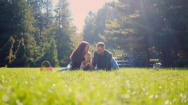 Aile pikniği, altın güneş ışığı banyosu, parkta elmaları ve kahkahaları paylaşmak. Sıcak bir sonbahar öğleden sonrasında, bir aile çimlerin üzerinde basit bir pikniğin tadını çıkarıyor. Tatlı gülüşler ve paylaşılan elmalar, parkta bir ailenin neşesi. Aile bağları güçlenir. 