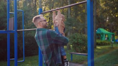 Bir babanın hafif kaldırışı, bir çocuğun neşeli gülüşü sonbahar havasında yankılanıyor. Açık hava eğlencesi, mutlu bir çocuk ve bir babanın sevgi dolu desteği. Sıcak bir öğleden sonra güneşi, sevgi dolu bir kucaklama ve genç bir kızın tatmin edici salıncağı. Park oyunu, bir babanın güçlü kolları.