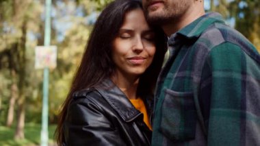 Güneşten sırılsıklam olmuş bir parkta bir erkekle bir kadının yakın kucaklaşması. Mutlu sevgili çift, sonbahar yaprakları arasında hassas bir anı paylaşıyor. Yüzler birbirine yakın, parkın kollarında bir bağ hissedildi. Sessiz bir park ortamında samimiyet ve samimiyet. Bir park karşılaşması, aşkım. 