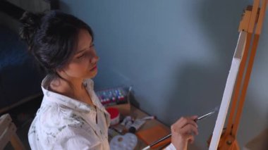 Sanatçı, sehpada beyaz bir tuval üzerinde bir fırça ile soyut bir tablo çizer. Beyaz bluzlu bir kadın stüdyoda parlak renklerle bir resim çiziyor. Sanatçının eli zarafetle hareket eder, tuvale bir güzellik sahnesi çizer. 