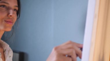 Sanatçı, sehpada beyaz bir tuval üzerinde bir fırça ile soyut bir tablo çizer. Beyaz bluzlu bir kadın stüdyoda parlak renklerle bir resim çiziyor. Sanatçının eli zarafetle hareket eder, tuvale bir güzellik sahnesi çizer. 