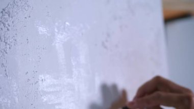 Sanatçı, sehpada beyaz bir tuval üzerinde bir fırça ile soyut bir tablo çizer. Beyaz bluzlu bir kadın stüdyoda parlak renklerle bir resim çiziyor. Sanatçının eli zarafetle hareket eder, tuvale bir güzellik sahnesi çizer. 