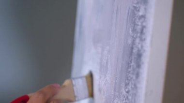Bir resim çizen bir fırçanın yakın çekimi. Sanatçı tuvalde bir resim yaratıyor. Bir kadın, bir sanat stüdyosundaki beyaz kağıda soyut bir resim çiziyor..