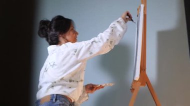 Sanatçı, sehpada beyaz bir tuval üzerinde bir fırça ile soyut bir tablo çizer. Beyaz bluzlu bir kadın stüdyoda parlak renklerle bir resim çiziyor. Sanatçının eli zarafetle hareket eder, tuvale bir güzellik sahnesi çizer. 