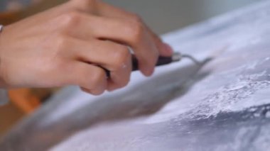 Sanatçı, sehpada beyaz bir tuval üzerinde bir fırça ile soyut bir tablo çizer. Beyaz bluzlu bir kadın stüdyoda parlak renklerle bir resim çiziyor. Sanatçının eli zarafetle hareket eder, tuvale bir güzellik sahnesi çizer. 