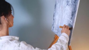 Sanatçı, sehpada beyaz bir tuval üzerinde bir fırça ile soyut bir tablo çizer. Beyaz bluzlu bir kadın stüdyoda parlak renklerle bir resim çiziyor. Sanatçının eli zarafetle hareket eder, tuvale bir güzellik sahnesi çizer. 