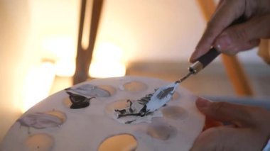 Makro fırça ve palet ve boya. Sanatçı tuvalde bir resim yaratıyor. Bir kadın, bir sanat stüdyosundaki beyaz kağıda soyut bir resim çiziyor..