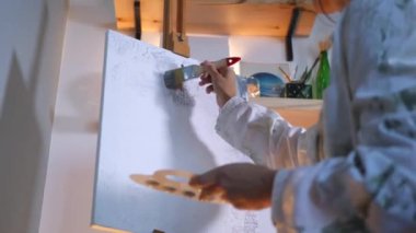 Sanatçı, sehpada beyaz bir tuval üzerinde bir fırça ile soyut bir tablo çizer. Beyaz bluzlu bir kadın stüdyoda parlak renklerle bir resim çiziyor. Sanatçının eli zarafetle hareket eder, tuvale bir güzellik sahnesi çizer. 