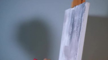 Sanatçı, sehpada beyaz bir tuval üzerinde bir fırça ile soyut bir tablo çizer. Beyaz bluzlu bir kadın stüdyoda parlak renklerle bir resim çiziyor. Sanatçının eli zarafetle hareket eder, tuvale bir güzellik sahnesi çizer. 