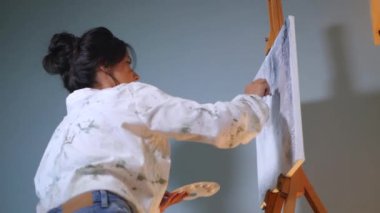 Sanatçı, sehpada beyaz bir tuval üzerinde bir fırça ile soyut bir tablo çizer. Beyaz bluzlu bir kadın stüdyoda parlak renklerle bir resim çiziyor. Sanatçının eli zarafetle hareket eder, tuvale bir güzellik sahnesi çizer. 