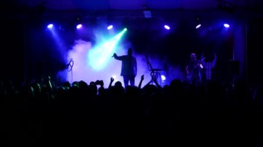 Kulüpte rock konseri. Gece kulübü partisi. Rock grubu rock festivalinde çalıyor. İnsanlar rock dinler. Renkli sahne ışıklarıyla çevrili. yavaş çekim