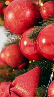 Dikey. Geleneksel Noel ağacı kırmızı süslemelerle süslenmiş. Güzel dekore edilmiş Noel ağacı olan şenlik odası. Kırmızı takılar bir tatil ağacına renk katıyor. Samimi ayarlar