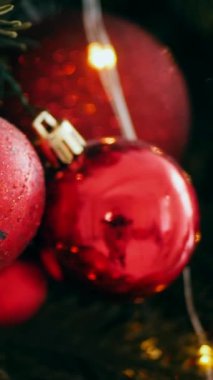 Dikey. Geleneksel Noel ağacı kırmızı süslemelerle süslenmiş. Güzel dekore edilmiş Noel ağacı olan şenlik odası. Kırmızı takılar bir tatil ağacına renk katıyor. Samimi ayarlar