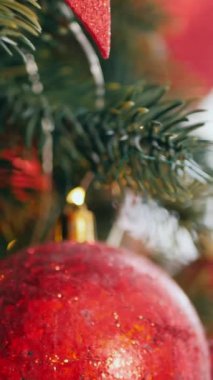 Dikey. Geleneksel Noel ağacı kırmızı süslemelerle süslenmiş. Güzel dekore edilmiş Noel ağacı olan şenlik odası. Kırmızı takılar bir tatil ağacına renk katıyor. Samimi ayarlar