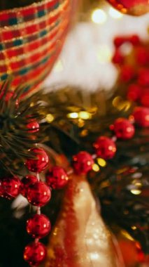 Dikey. Geleneksel Noel ağacı kırmızı süslemelerle süslenmiş. Güzel dekore edilmiş Noel ağacı olan şenlik odası. Kırmızı takılar bir tatil ağacına renk katıyor. Samimi ayarlar