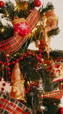 Dikey. Geleneksel Noel ağacı kırmızı süslemelerle süslenmiş. Güzel dekore edilmiş Noel ağacı olan şenlik odası. Kırmızı takılar bir tatil ağacına renk katıyor. Samimi ayarlar
